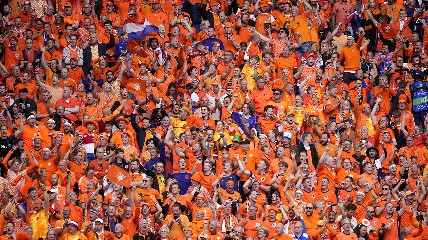 Oranje gekleed publiek juicht op een stadion tijdens een wedstrijd.