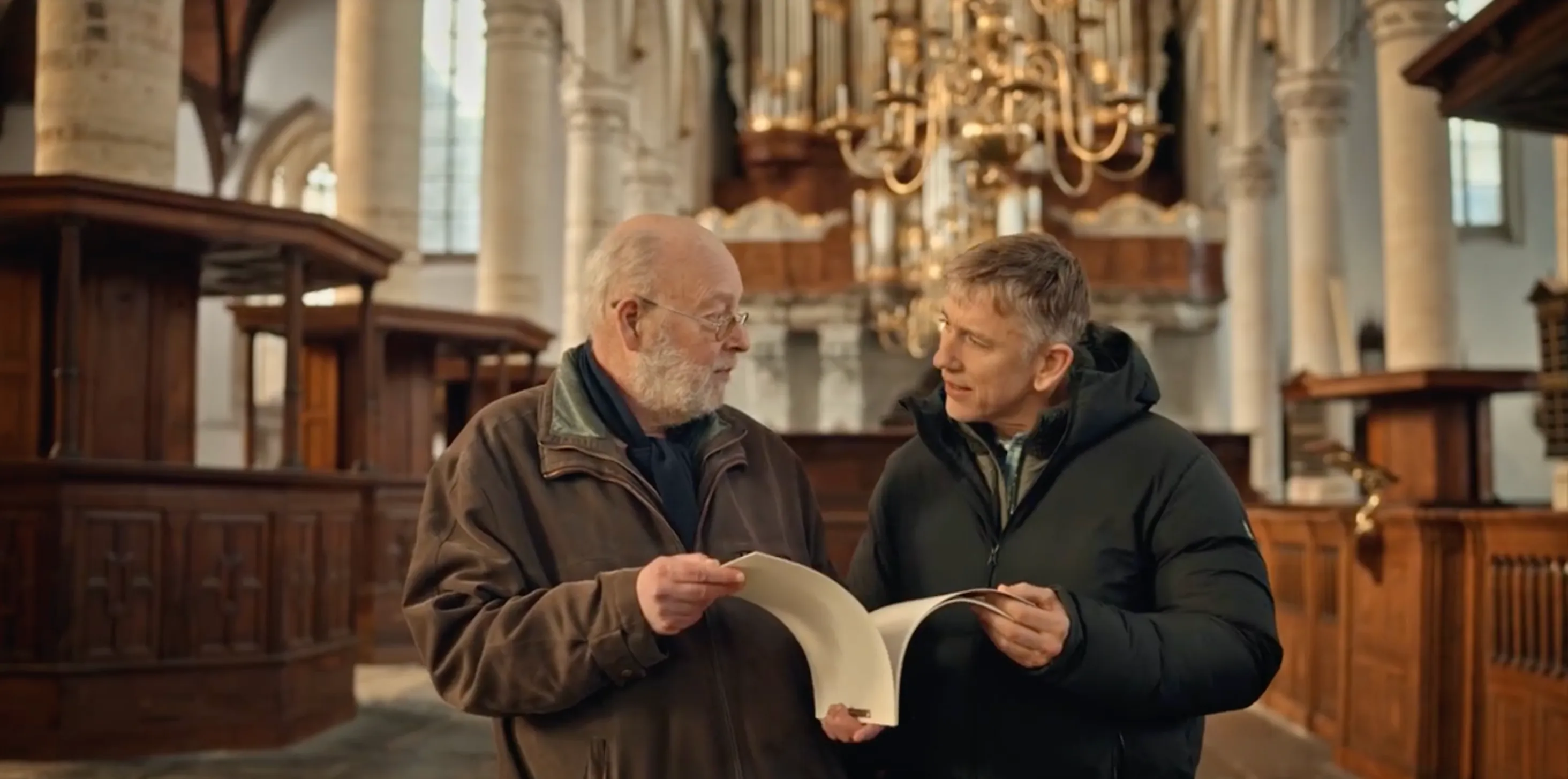 Twee mannen in een kerk, kijkend naar een boek.