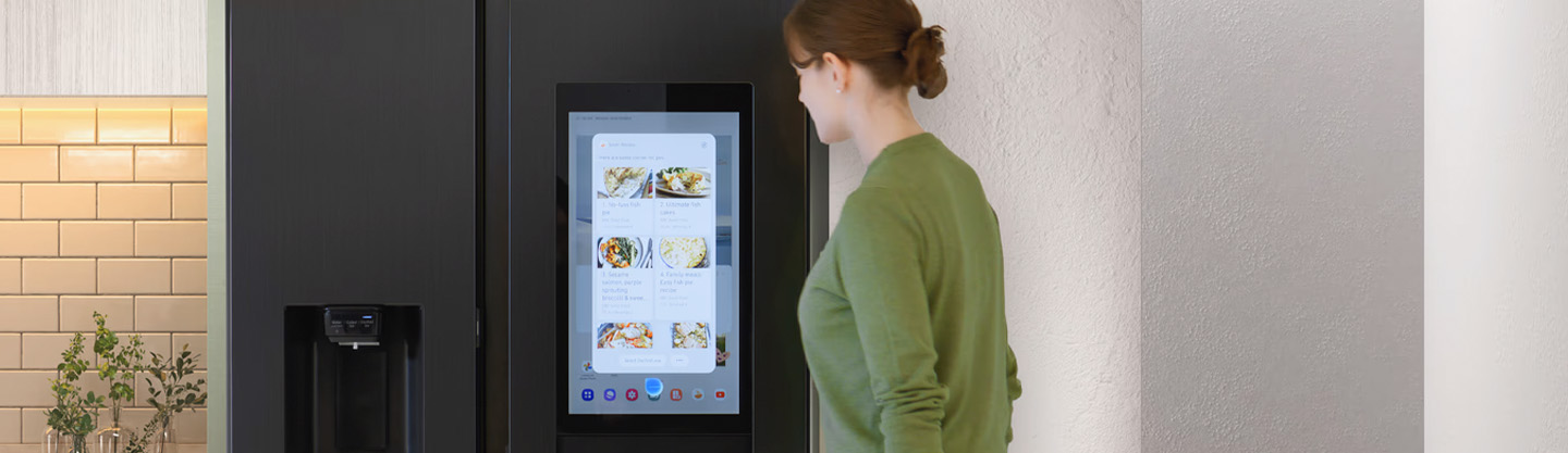 Een persoon kijkt naar het digitale scherm op een moderne koelkast.