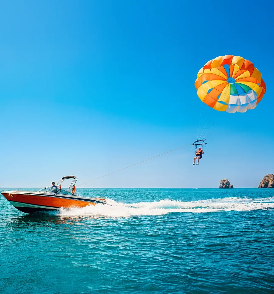 Een boot met een parasail in de lucht boven een blauwe zee.