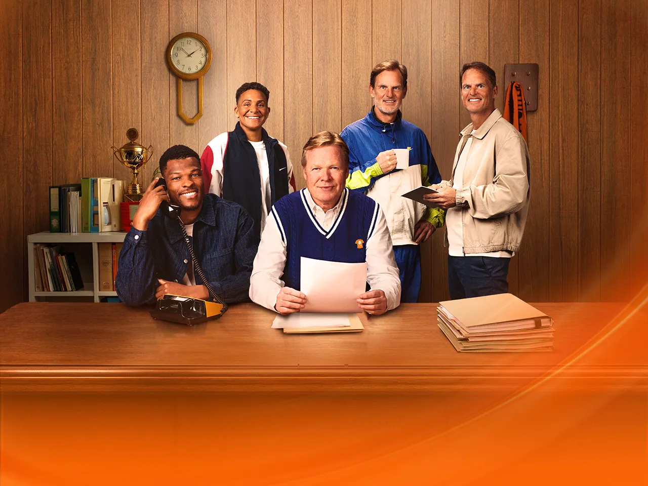 Zes mensen in een kantooromgeving, met een houten achtergrond en een klok aan de muur.