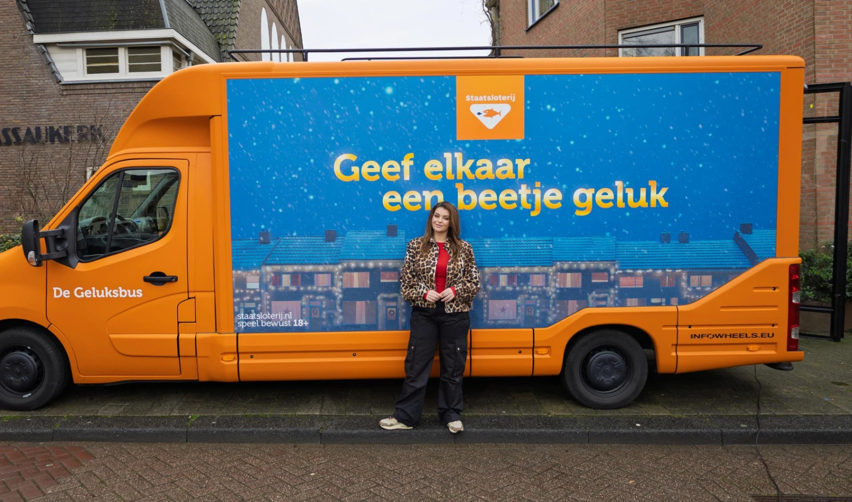 Oranje Geluksbus van Staatsloterij met de tekst 'Geef elkaar een beetje geluk'